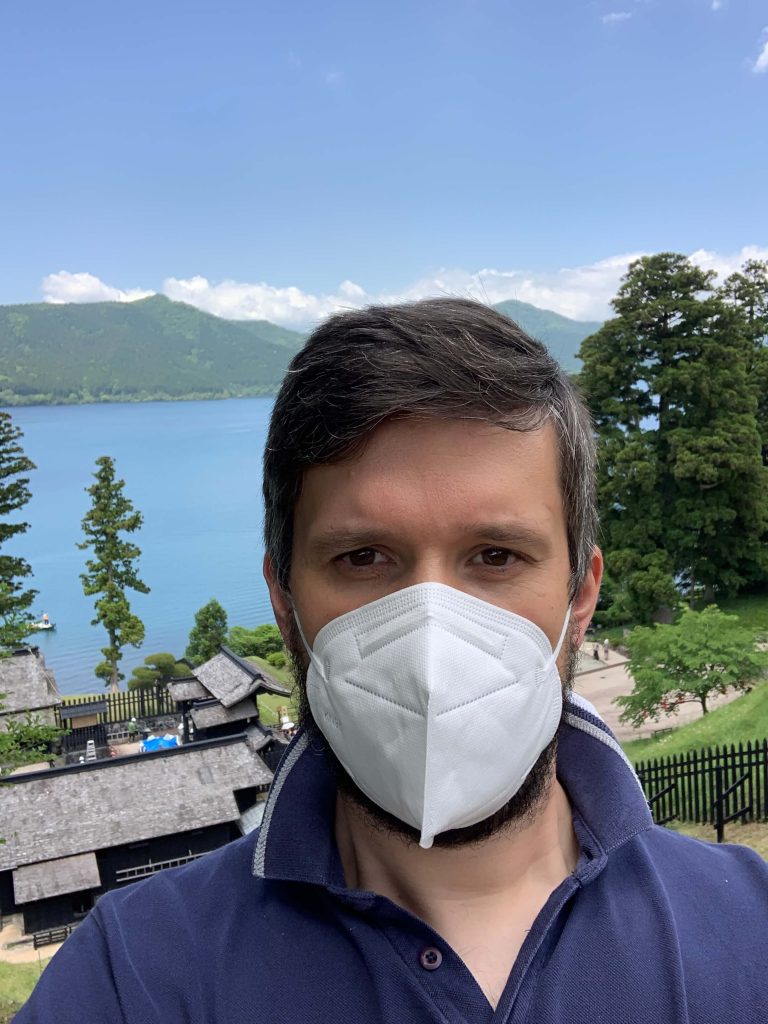 Vlad wearing a white face mask in Hakone with Japanese cedar trees visible in the background during pollen season