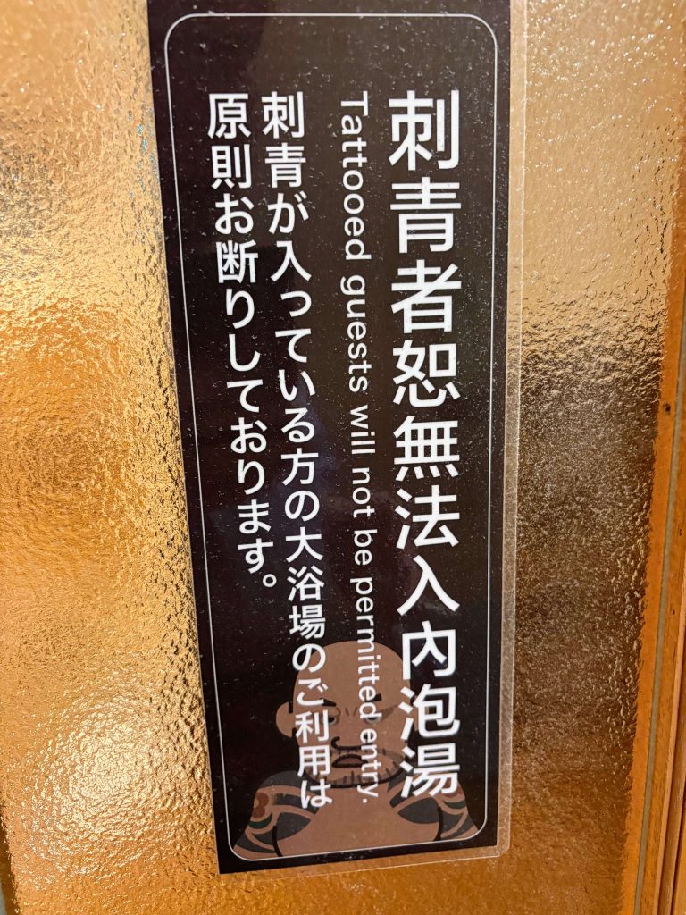 A sign in English and Japanese, saying that Tattooed guests will not be permitted to enter onsen.
